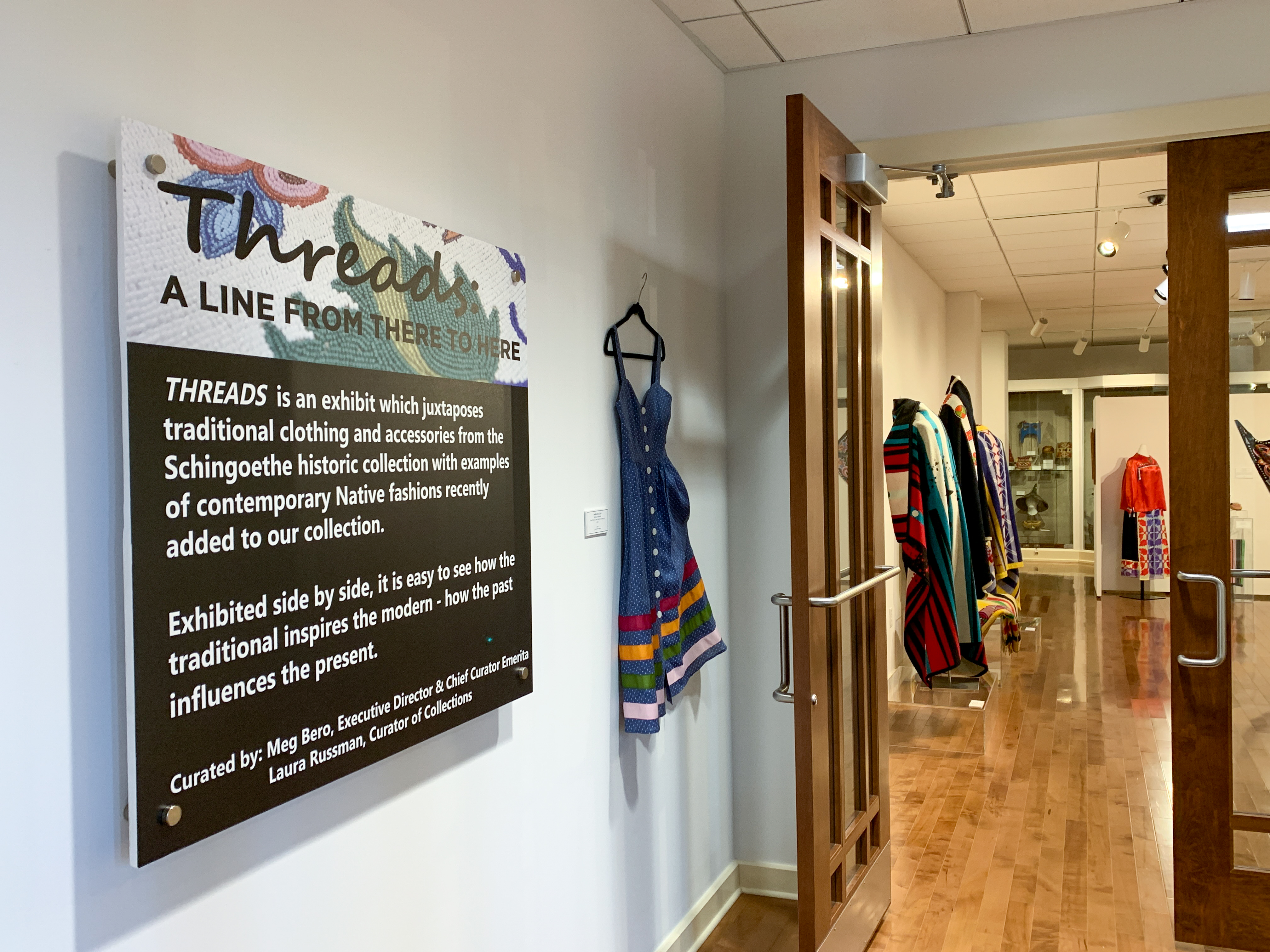 Museum entryway with "Threads" sign and dress